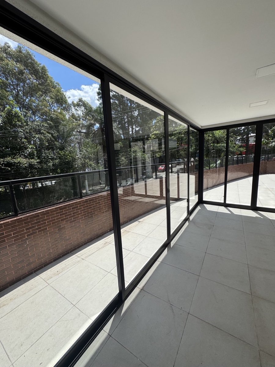 Porta de correr de 4 folhas em alumínio preto da linha Suprema, vista interna da varanda.