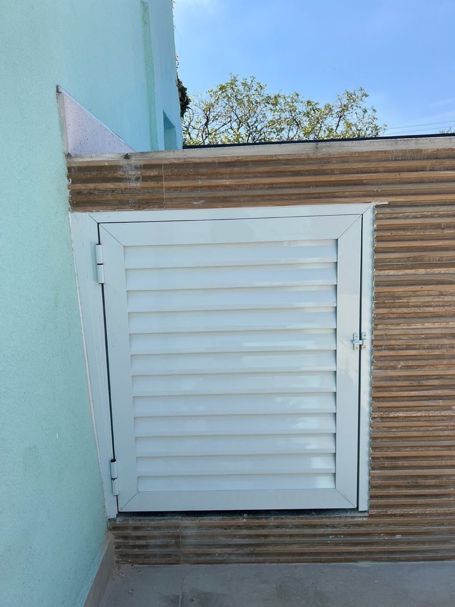 Veneziana de alumínio branco instalada em muro externo.