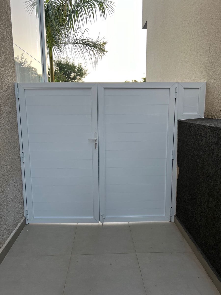 Porta de alumínio de duas folhas com lambril branco, instalada em área externa.