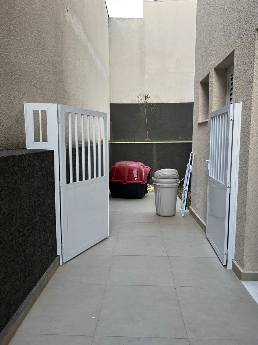 Portão de duas folhas em alumínio branco com gradil vertical.