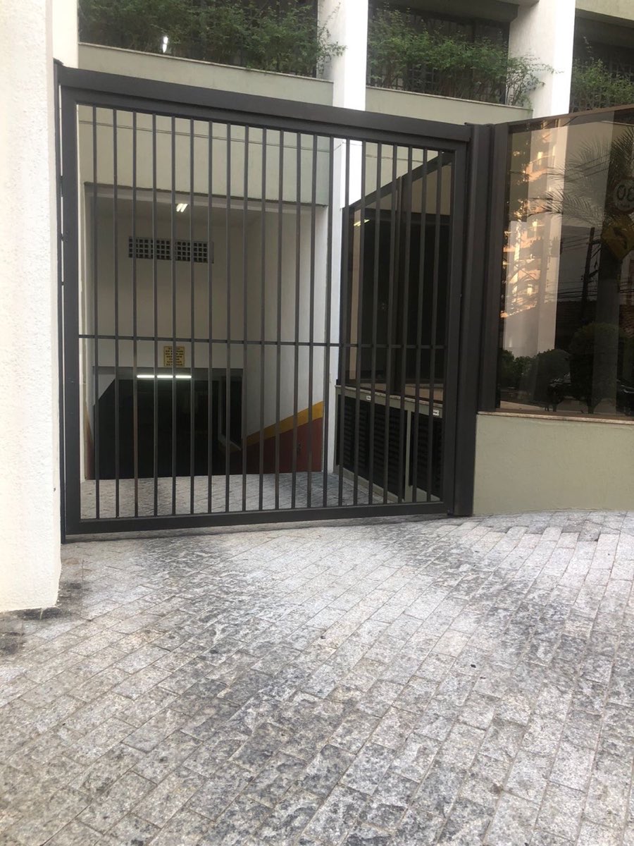 Portão de alumínio preto com gradil vertical na entrada de um edifício.