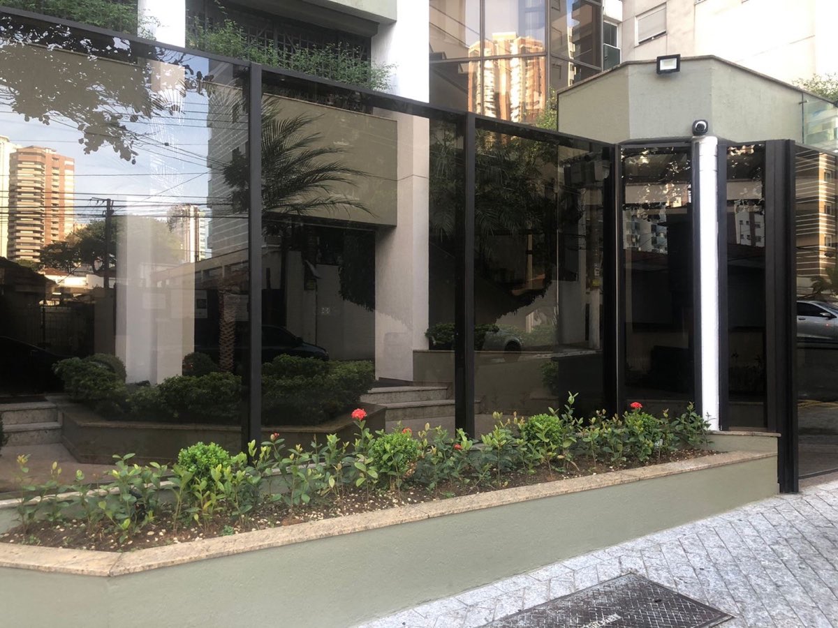 Fachada de edifício com esquadrias e portão em alumínio preto.
