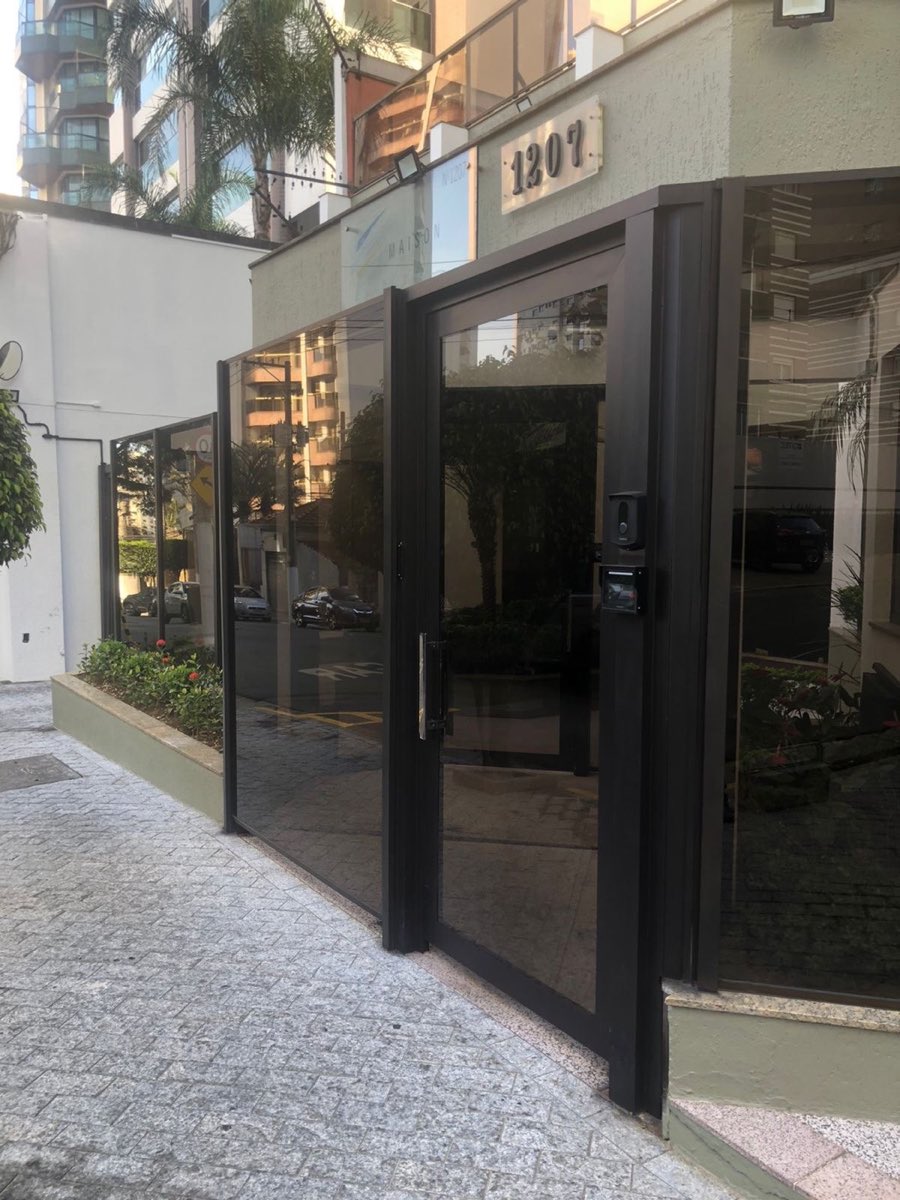 Porta de vidro emoldurada por esquadria de alumínio preto na entrada.