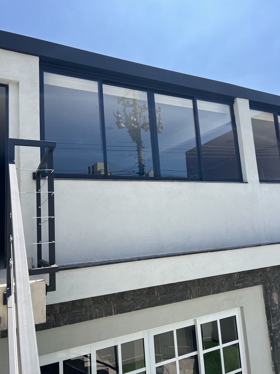 Fachada de imóvel com fita corrida de janelas em alumínio preto e vidro, vista da rua.