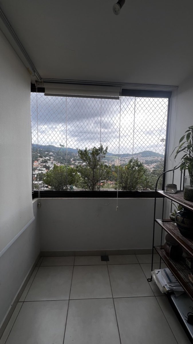 Sacada de apartamento fechada com envidraçamento de vidro retrátil e vista para a cidade.