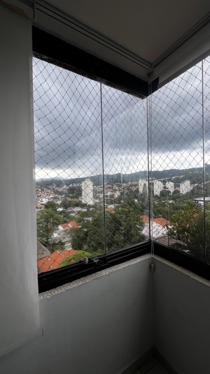 Sacada envidraçada com painéis de vidro recolhidos, vista ampla para a cidade.