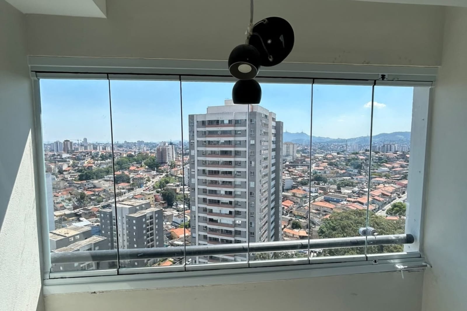 Sacada de apartamento envidraçada em andar alto, com esquadria branca e vista panorâmica da Zona Norte. Obra da VitraAlu em Freguesia do Ó, São Paulo.